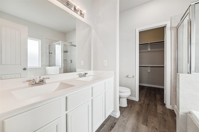 3685 Cub Dr, Conroe, TX 77301 - full bath featuring a stall shower, toilet, double vanity, a walk in closet, and wood finished floors
