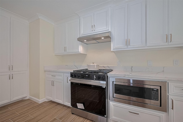 7130 Walkway St, Houston, TX 77036 - kitchen featuring gas stove, under cabinet range hood, stainless steel microwave, white cabinets, and wood finish floors