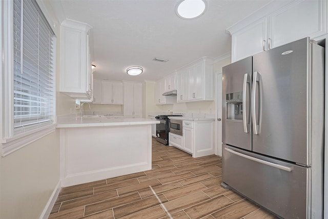 7130 Walkway St, Houston, TX 77036 - kitchen with appliances with stainless steel finishes, wood finish floors, white cabinets, light countertops, and baseboards