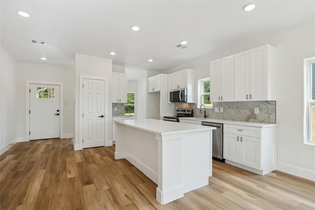 3708 Avenue S, Santa Fe, TX 77510 - kitchen with appliances with stainless steel finishes, tasteful backsplash, light wood-style flooring, white cabinets, and recessed lighting
