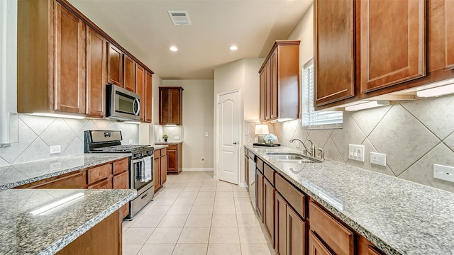 32706 Oak Heights Ln, Brookshire, TX 77423 - kitchen with appliances with stainless steel finishes, a sink, baseboards, stone countertops, and light tile patterned floors
