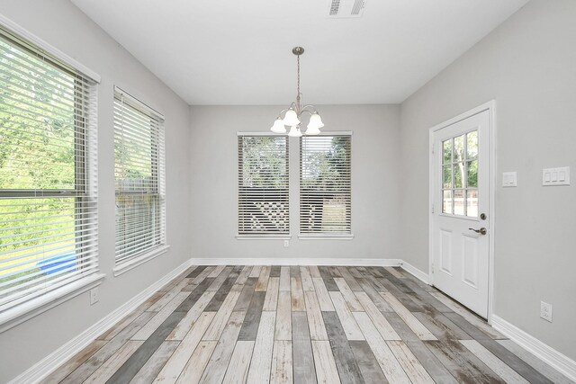 25450 Killarney St, Hempstead, TX 77445 - unfurnished dining area with a chandelier, light wood-style floors, and baseboards