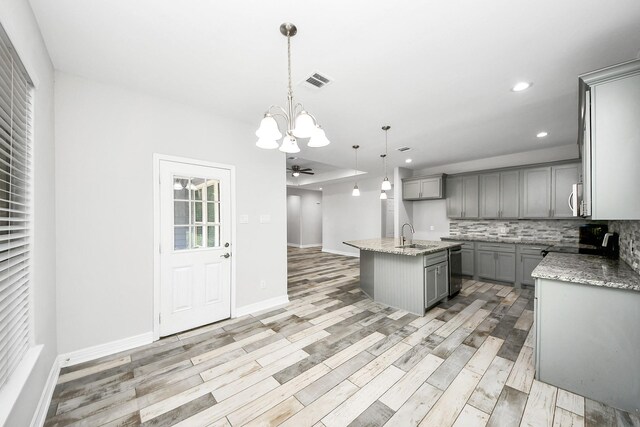 25450 Killarney St, Hempstead, TX 77445 - kitchen featuring gray cabinets, a chandelier, decorative backsplash, light stone countertops, and light wood-style floors