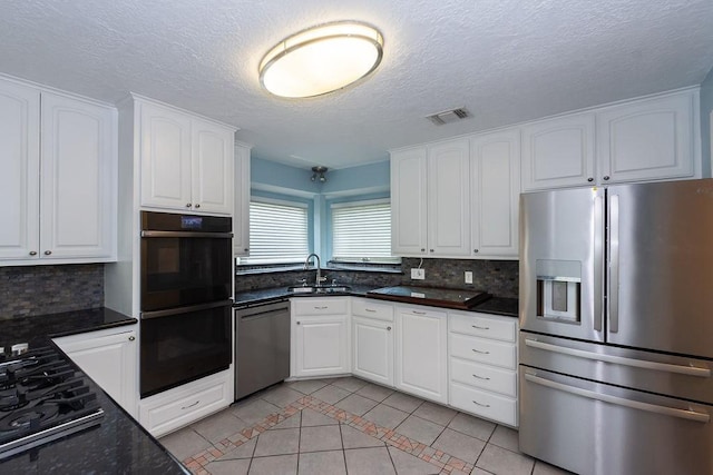 6310 Gleneagles Dr, Pasadena, TX 77505 - kitchen featuring stainless steel appliances, light tile patterned floors, tasteful backsplash, white cabinetry, and a textured ceiling