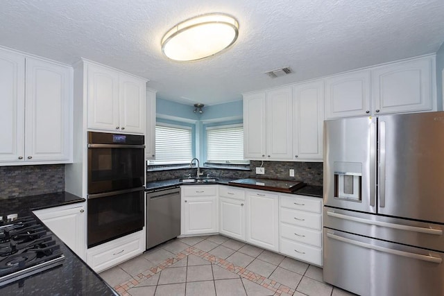 6310 Gleneagles Dr, Pasadena, TX 77505 - kitchen with stainless steel appliances, light tile patterned floors, decorative backsplash, white cabinetry, and a textured ceiling
