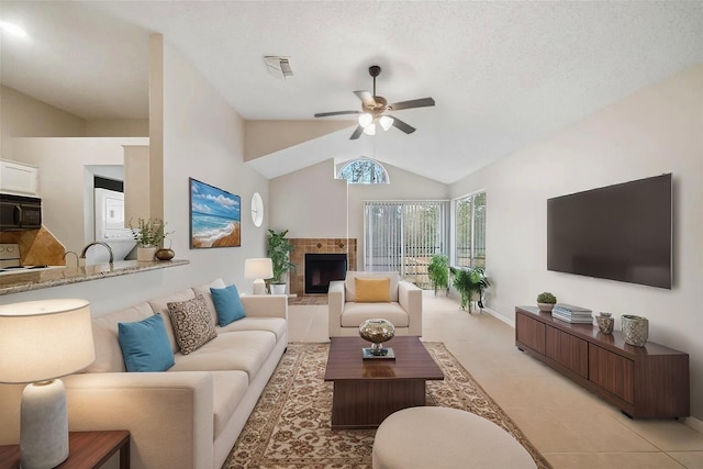 3317 Golden Trails Dr Unit 802, Houston, TX 77345 - living room featuring stacked washer and clothes dryer, a ceiling fan, a tile fireplace, vaulted ceiling, and light tile patterned floors