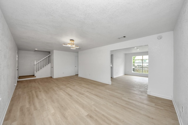 3223 Deer Valley Dr, Spring, TX 77373 - unfurnished room featuring light wood-type flooring, stairway, a textured ceiling, baseboards, and a chandelier