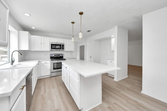 3223 Deer Valley Dr, Spring, TX 77373 - kitchen featuring appliances with stainless steel finishes, a center island, a sink, light wood-style floors, and white cabinets