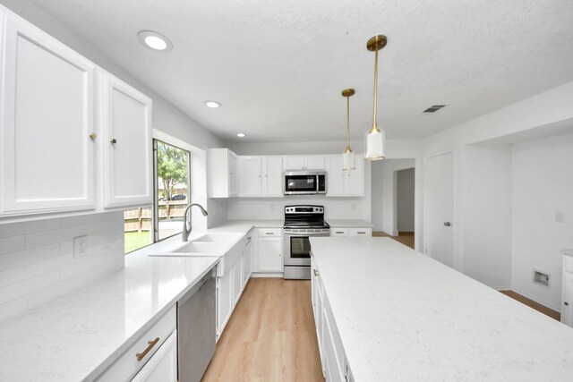 3223 Deer Valley Dr, Spring, TX 77373 - kitchen featuring appliances with stainless steel finishes, a sink, backsplash, white cabinets, and light wood-type flooring
