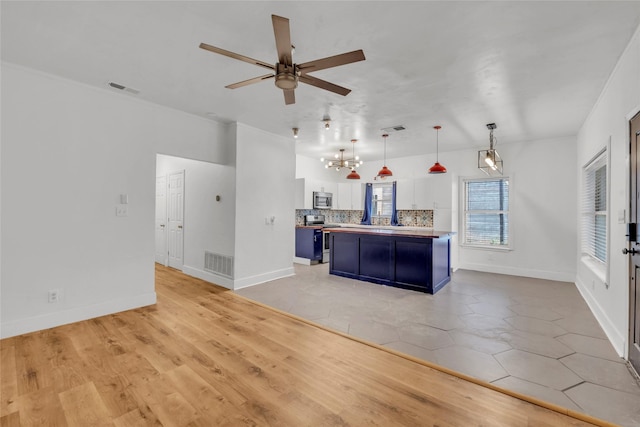 1138 Northwestern Ave, Austin, TX 78702 - kitchen with stainless steel appliances, blue cabinets, a chandelier, white cabinetry, and a ceiling fan