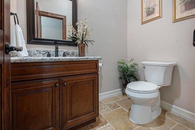 1827 E Cedar Bayou Lynchburg Rd, Baytown, TX 77521 - half bathroom featuring baseboards, toilet, stone tile flooring, and vanity