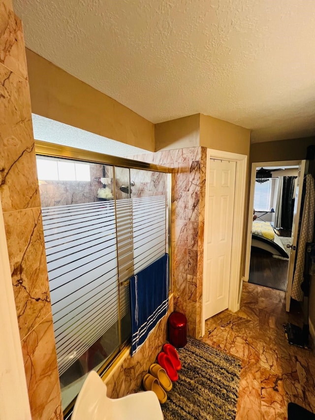 6639 Seaton Valley Dr, Spring, TX 77379 - ensuite bathroom featuring a shower with shower door and a textured ceiling
