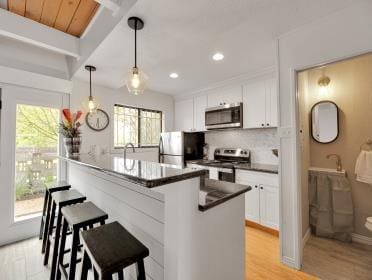 3809 N Braeswood Unit 14, Houston, TX 77025 - kitchen featuring stainless steel appliances, dark countertops, light wood-style flooring, white cabinetry, and recessed lighting