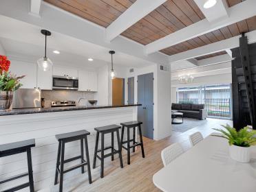 3809 N Braeswood Unit 14, Houston, TX 77025 - kitchen with stainless steel microwave, tasteful backsplash, wood ceiling with exposed beams, pendant lighting, and a kitchen bar