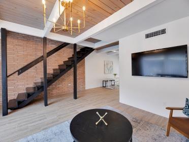 3809 N Braeswood Unit 14, Houston, TX 77025 - living area with wood finished floors, a chandelier, stairway, wood ceiling with exposed beams, and brick wall