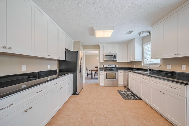 3705 Autumn Ln, Baytown, TX 77521 - kitchen featuring appliances with stainless steel finishes, a sink, a textured ceiling, white cabinetry, and dark countertops