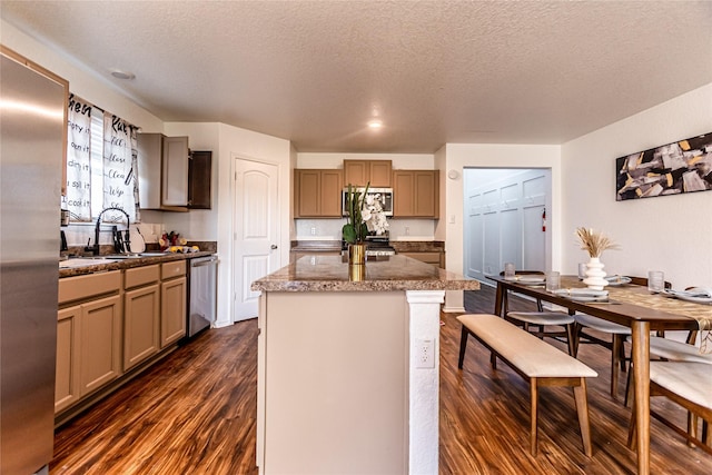 3240 Mission Riv, San Antonio, TX 78245 - kitchen featuring a textured ceiling, stainless steel appliances, a kitchen island, dark wood-style flooring, and a sink