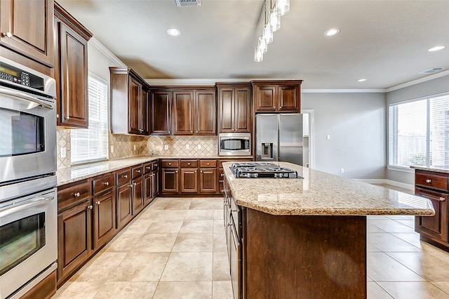 4706 Payton Chase Ln, Katy, TX 77494 - kitchen with appliances with stainless steel finishes, crown molding, light tile patterned floors, decorative backsplash, and a center island