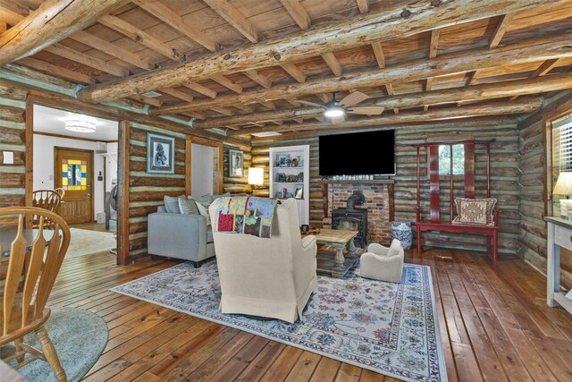 1356 Pegoda Ranch Rd, Woodlake, TX 75865 - living area with hardwood / wood-style flooring, log walls, a wood stove, wooden ceiling with exposed beams, and ceiling fan