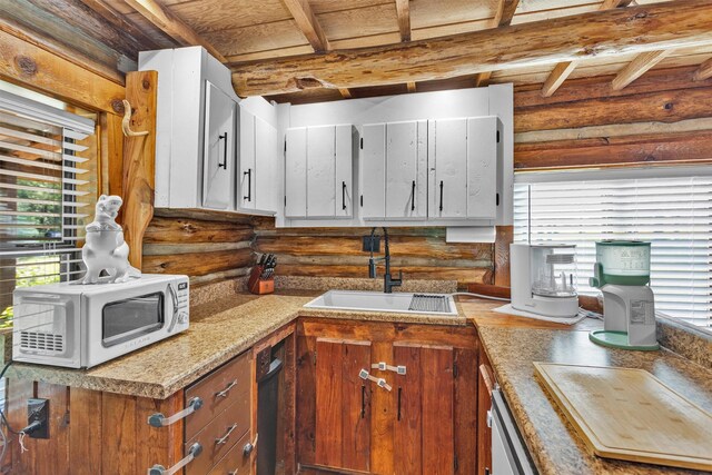 1356 Pegoda Ranch Rd, Woodlake, TX 75865 - kitchen featuring a sink, rustic walls, light countertops, white microwave, and brown cabinets