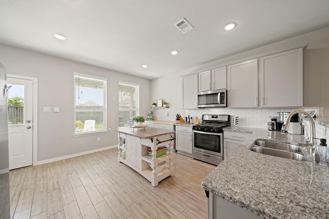 7410 Arabian Moon Trl, Fulshear, TX 77441 - kitchen featuring stainless steel appliances, open shelves, a sink, decorative backsplash, and baseboards