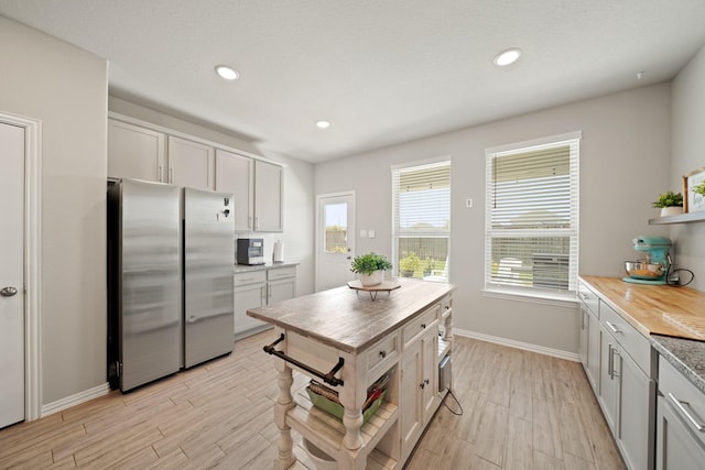7410 Arabian Moon Trl, Fulshear, TX 77441 - kitchen with freestanding refrigerator, open shelves, butcher block counters, baseboards, and light wood finished floors
