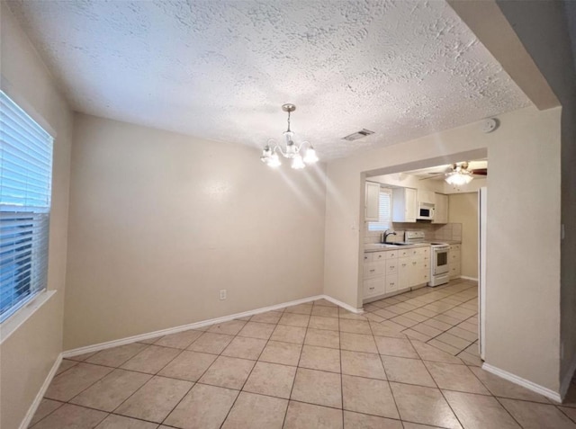 16307 Thistleglen Dr, Houston, TX 77095 - unfurnished living room with a chandelier, a textured ceiling, light tile patterned floors, baseboards, and ceiling fan