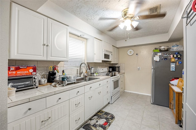 16307 Thistleglen Dr, Houston, TX 77095 - kitchen featuring white appliances, ceiling fan, a sink, tasteful backsplash, and white cabinetry