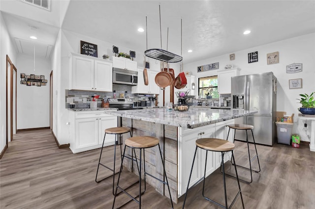 711 Forest Spgs, Livingston, TX 77351 - kitchen featuring stainless steel appliances, white cabinets, backsplash, a kitchen island, and a breakfast bar area