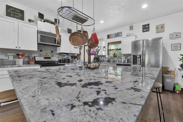 711 Forest Spgs, Livingston, TX 77351 - kitchen featuring appliances with stainless steel finishes, a kitchen bar, tasteful backsplash, a kitchen island, and white cabinets