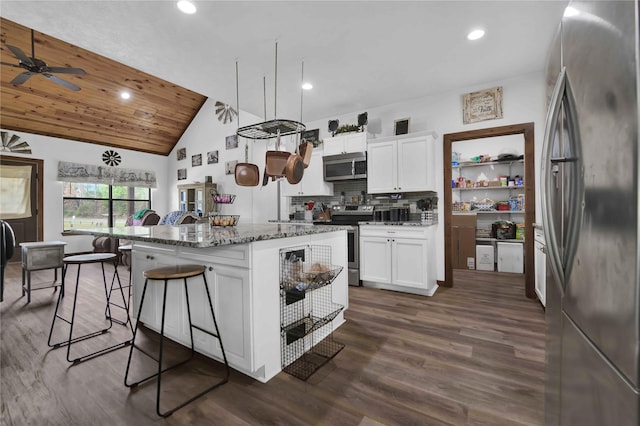 711 Forest Spgs, Livingston, TX 77351 - kitchen featuring stainless steel appliances, a center island, stone countertops, a kitchen bar, and dark wood-style flooring