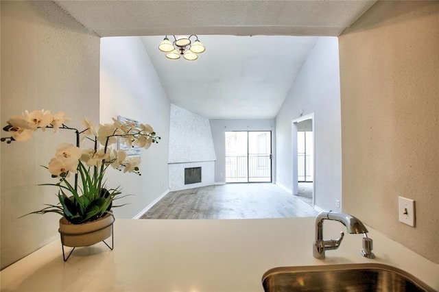 10075 Westpark Dr Unit 45, Houston, TX 77042 - living room featuring a brick fireplace, wood finished floors, lofted ceiling, baseboards, and a chandelier
