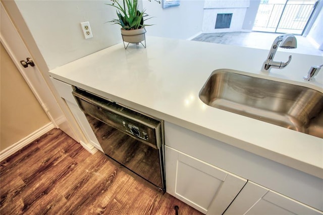 10075 Westpark Dr Unit 45, Houston, TX 77042 - kitchen featuring dishwasher, a sink, light countertops, dark wood-style flooring, and a fireplace