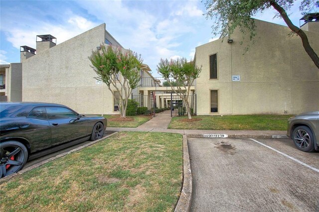 10075 Westpark Dr Unit 45, Houston, TX 77042 - view of property exterior featuring stucco siding, uncovered parking, and a yard