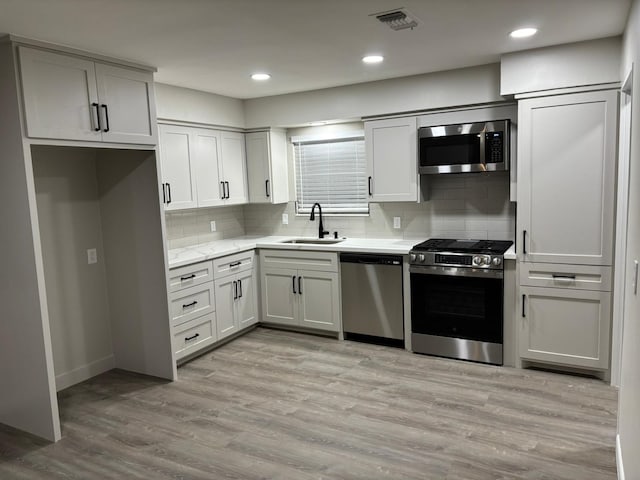 3706 Galway Ln, Houston, TX 77080 - kitchen featuring appliances with stainless steel finishes, a sink, decorative backsplash, light wood-style floors, and recessed lighting