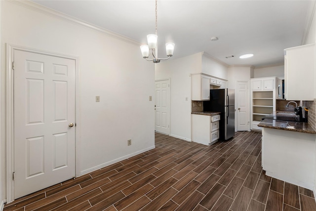 5515 Strack Rd Unit 101, Houston, TX 77069 - kitchen featuring freestanding refrigerator, crown molding, backsplash, white cabinetry, and a chandelier