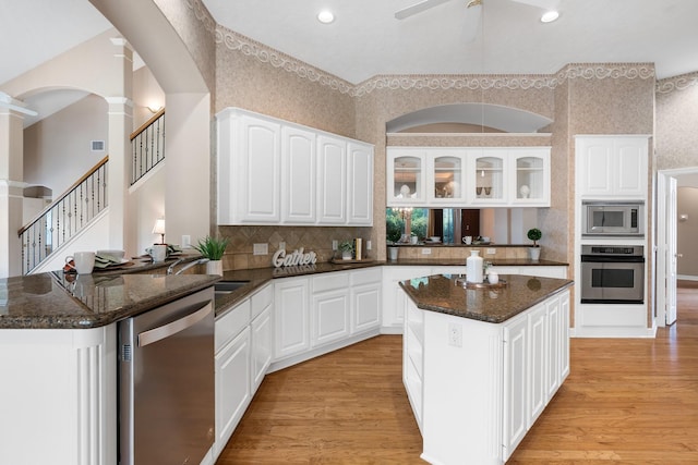 12027 Water Oak Dr, Magnolia, TX 77354 - kitchen with stainless steel appliances, ornate columns, a ceiling fan, light wood finished floors, and dark stone countertops