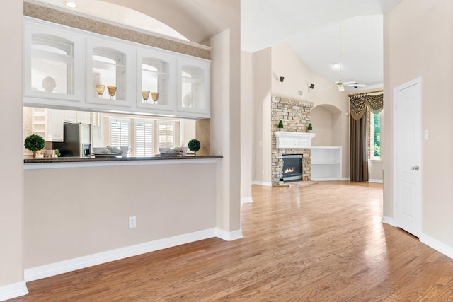12027 Water Oak Dr, Magnolia, TX 77354 - unfurnished living room with ceiling fan, wood finished floors, a stone fireplace, baseboards, and high vaulted ceiling