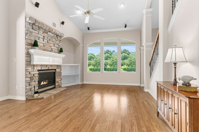 12027 Water Oak Dr, Magnolia, TX 77354 - unfurnished living room featuring ceiling fan, a stone fireplace, light wood-type flooring, and baseboards