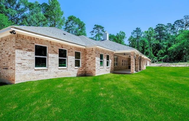 307 Grand Vw, Huntsville, TX 77340 - back of property featuring ceiling fan, a lawn, a patio area, a chimney, and a shingled roof