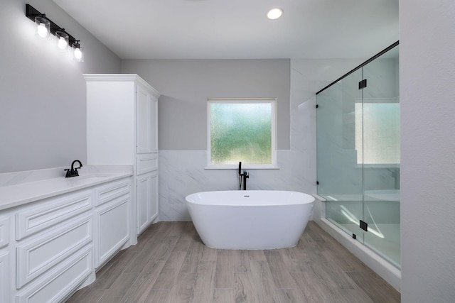 307 Grand Vw, Huntsville, TX 77340 - bathroom with a freestanding bath, a shower stall, vanity, tile walls, and wood finished floors