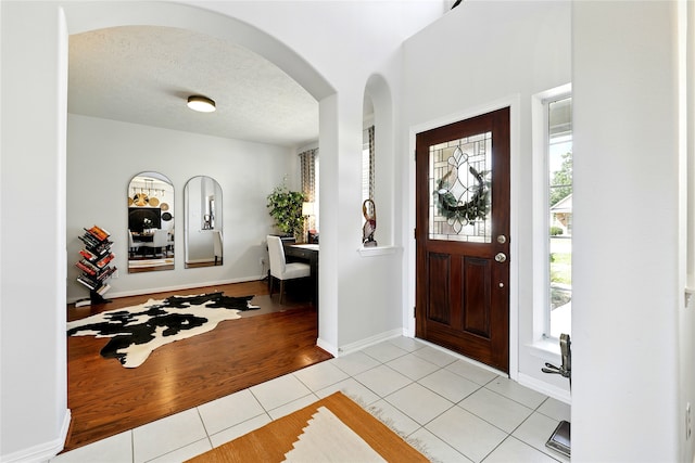 8210 Edenwood Dr, Spring, TX 77389 - foyer entrance featuring arched walkways, light tile patterned floors, a textured ceiling, and baseboards