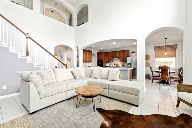 8210 Edenwood Dr, Spring, TX 77389 - living room featuring light tile patterned floors, a towering ceiling, arched walkways, and baseboards