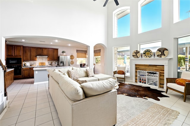8210 Edenwood Dr, Spring, TX 77389 - living area featuring light tile patterned floors, a towering ceiling, arched walkways, and ceiling fan