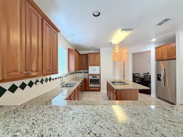522 Chickory Field Ln, Pearland, TX 77584 - kitchen featuring appliances with stainless steel finishes, a sink, light stone counters, decorative backsplash, and brown cabinets