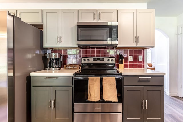 15135 Kamary Ln, San Antonio, TX 78247 - kitchen with stainless steel appliances, light countertops, decorative backsplash, gray cabinetry, and arched walkways