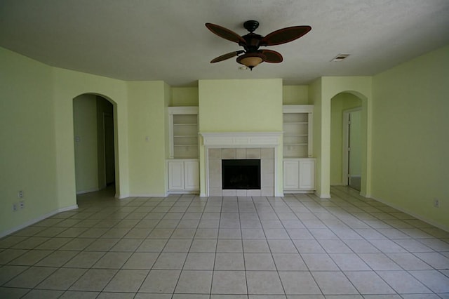 105 N Hollylaurel Cir, The Woodlands, TX 77382 - unfurnished living room featuring arched walkways, a ceiling fan, light tile patterned floors, baseboards, and a fireplace
