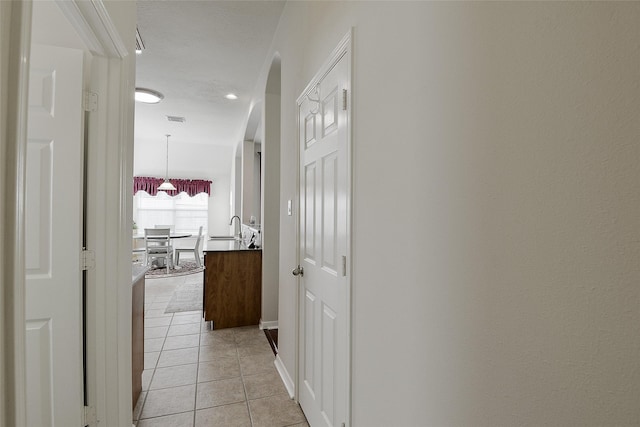 8810 Sailing Dr, Humble, TX 77346 - corridor with light tile patterned floors, a sink, arched walkways, and baseboards