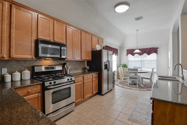 8810 Sailing Dr, Humble, TX 77346 - kitchen with appliances with stainless steel finishes, a sink, lofted ceiling, brown cabinetry, and backsplash