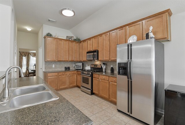 8810 Sailing Dr, Humble, TX 77346 - kitchen with appliances with stainless steel finishes, a sink, vaulted ceiling, light tile patterned floors, and decorative backsplash